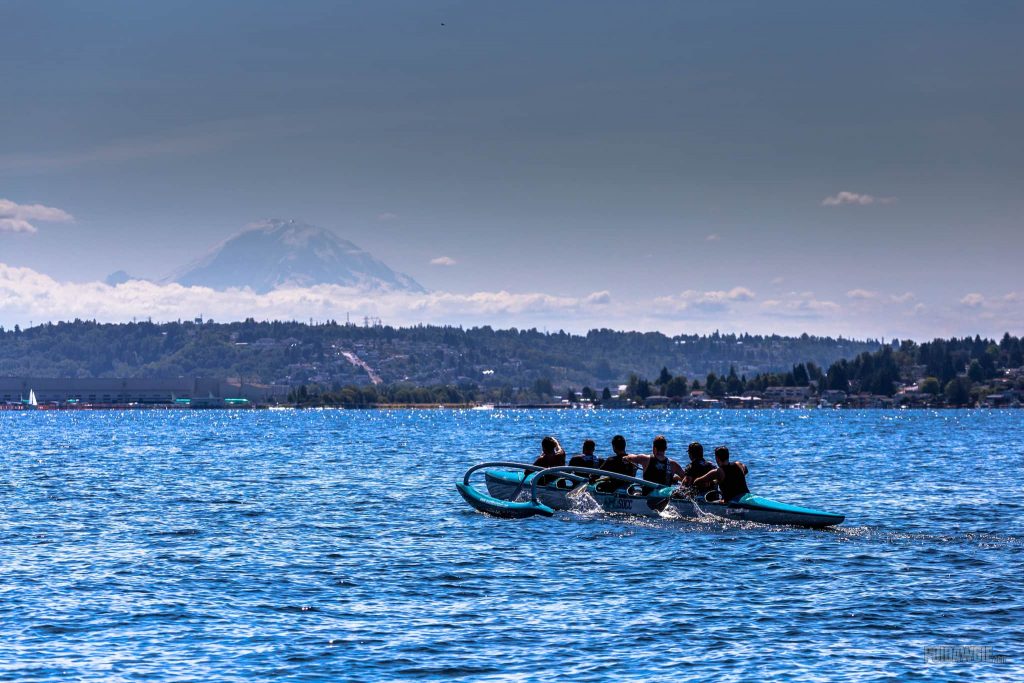 Men paddling outrigger canoe with Mt. Rainier in the background